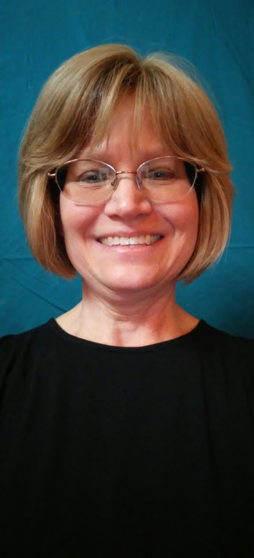 Caucasian woman smiling wearing black shirt.  Blonde hair bob cut to chin, blue eyes, glasses in front of a teal blue background.  She, Her, Hers.