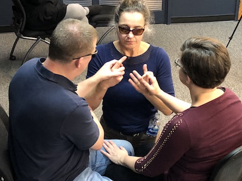A man and two women having a conversation using protactile ASL