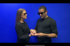 Roberto, Dominican Male in a dark shirt standing with sunglasses on, is using Protactile with another person.